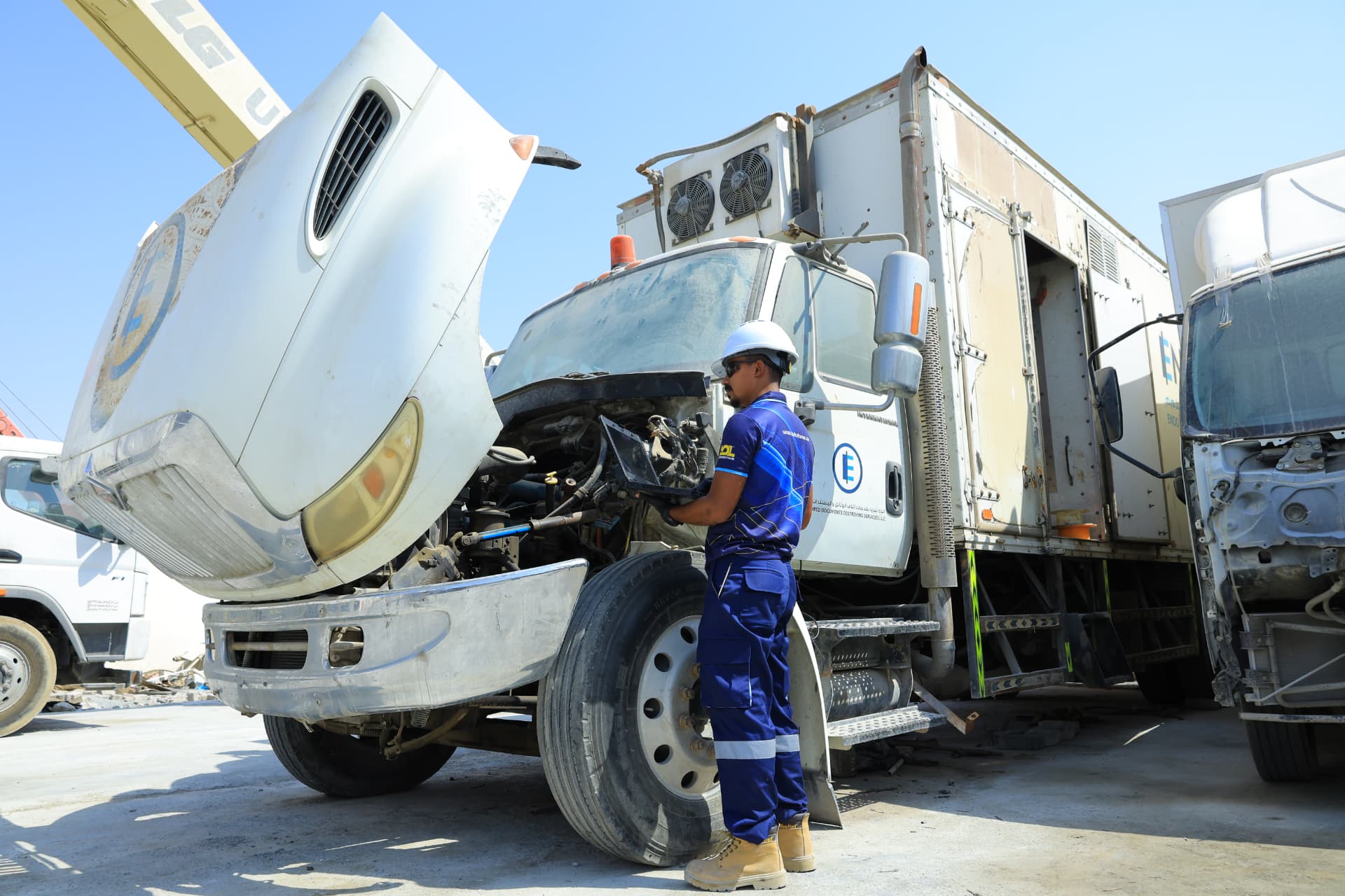 AutoDome technician running diagnostics on a refrigerated truck with its hood open